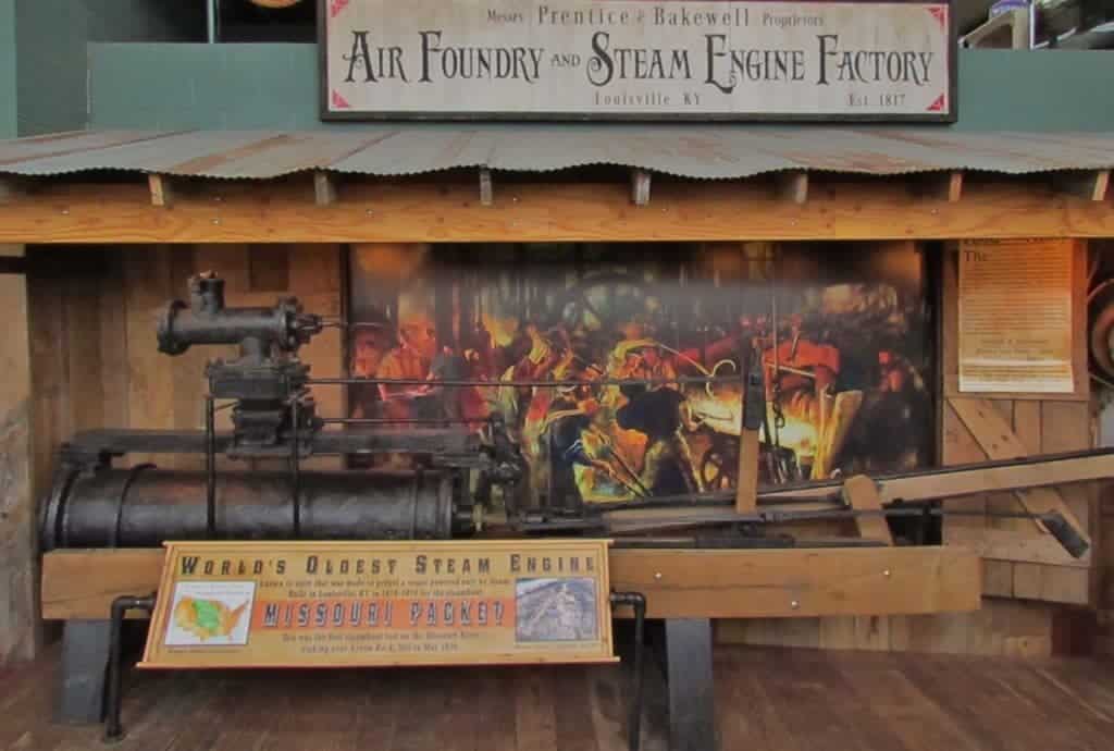 A large metal steam engine is displayed along with a sign denoting it as the "World's Oldest Steam Engine". 