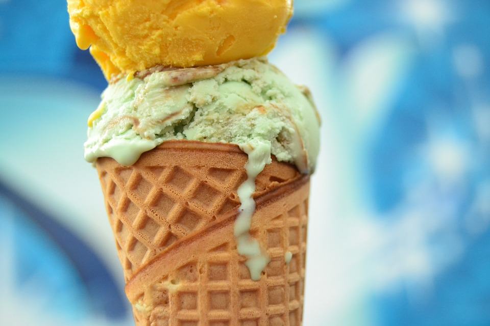 A sugar cone contains two scoops of ice cream.