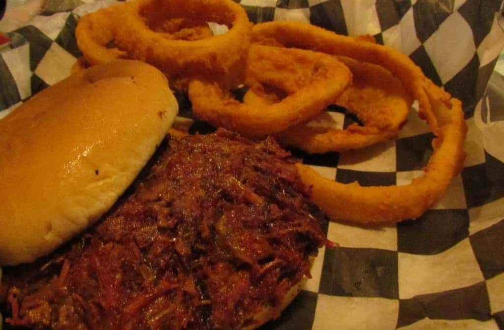 Beef brisket sandwich with onion rings.