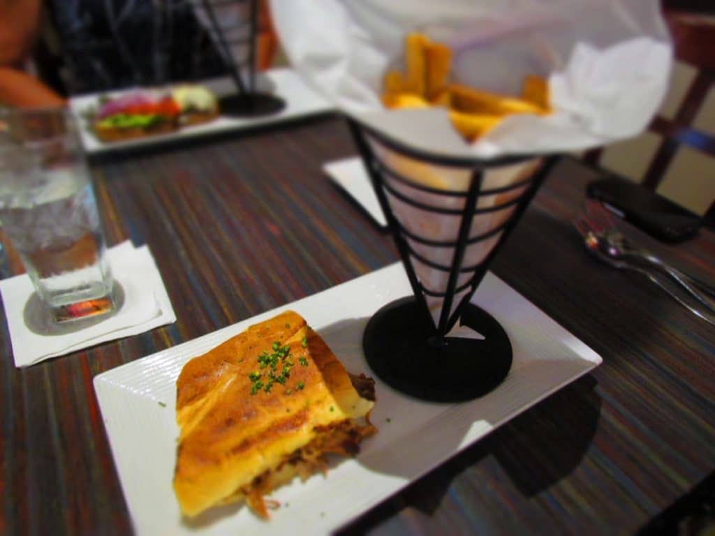 A plate filled with a Cuban sandwich and an order of french fries.