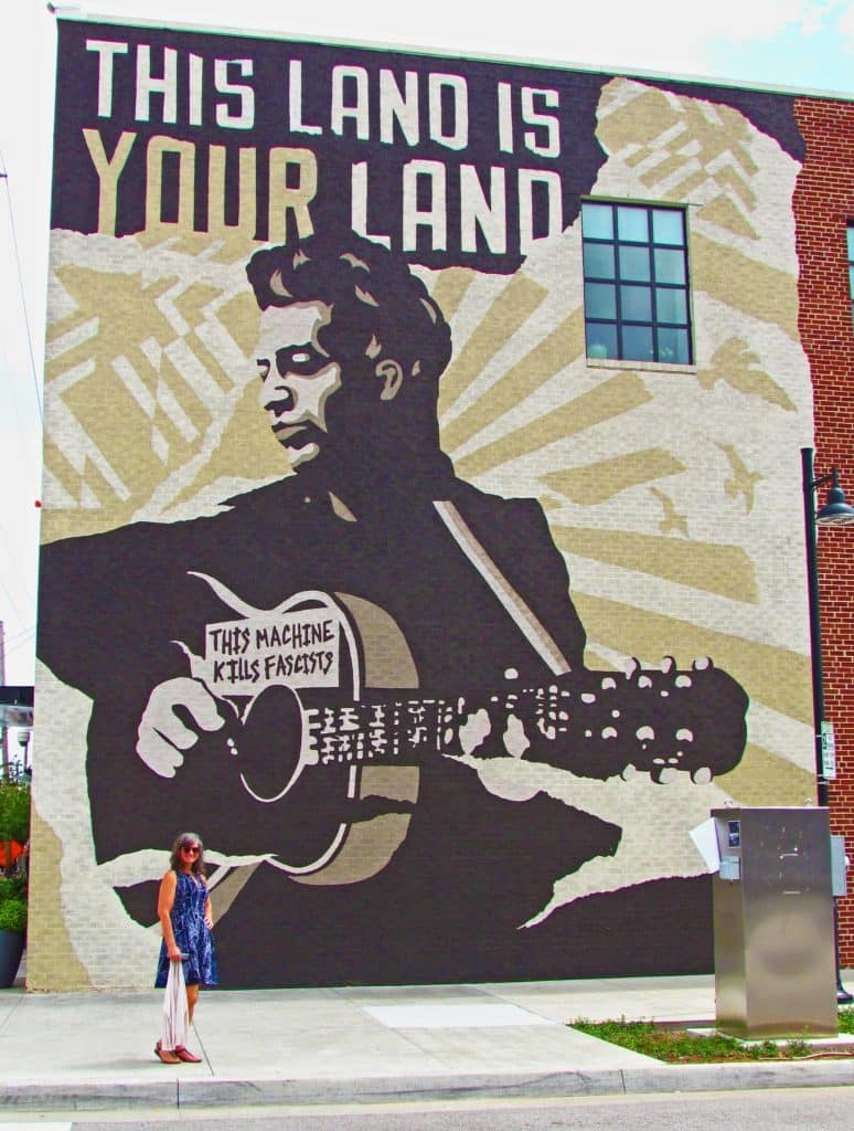 Crystal takes a moment to pose in front of the iconic mural on the side of the Woody Guthrie Center in Tulsa.