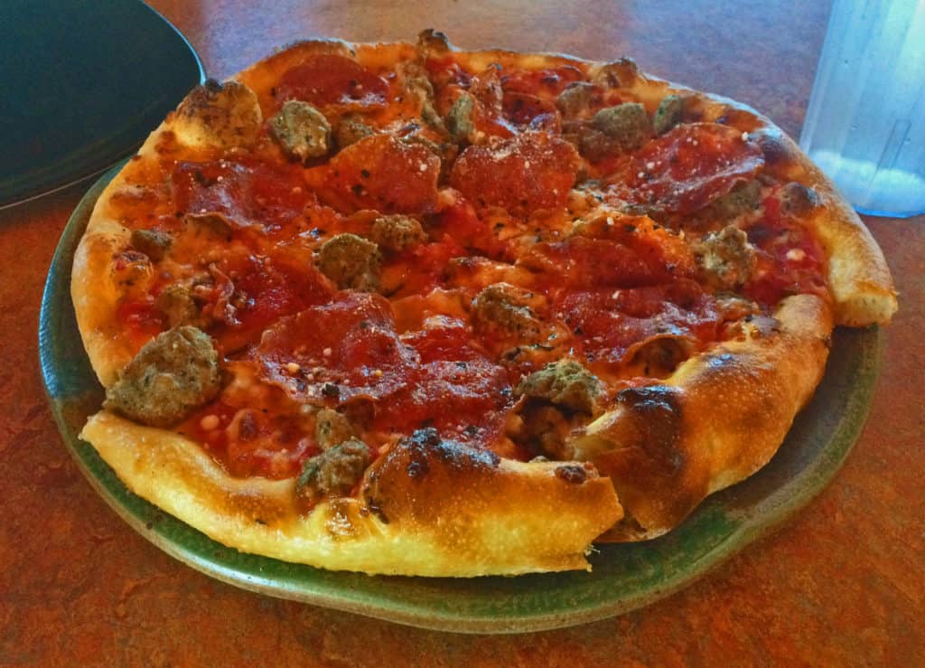 A plate is covered with the Tre Carne Pizza at Spin Neapolitan Pizza.