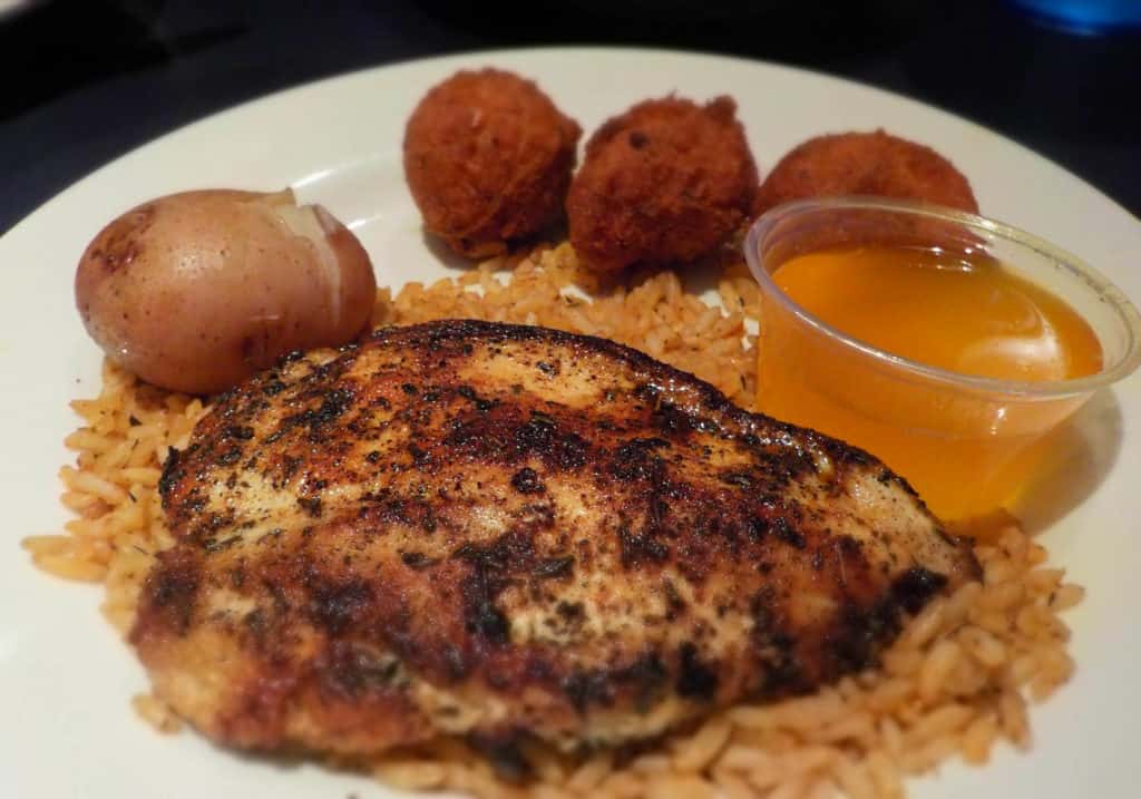 Blackened chicken rests on a bed of dirty rice.