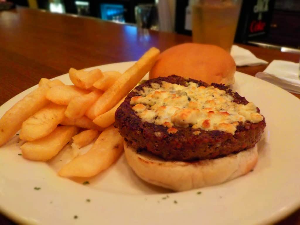 One of the Hereford House Steakburgers is topped with blue cheese, and accompanied by an order of steak fries.