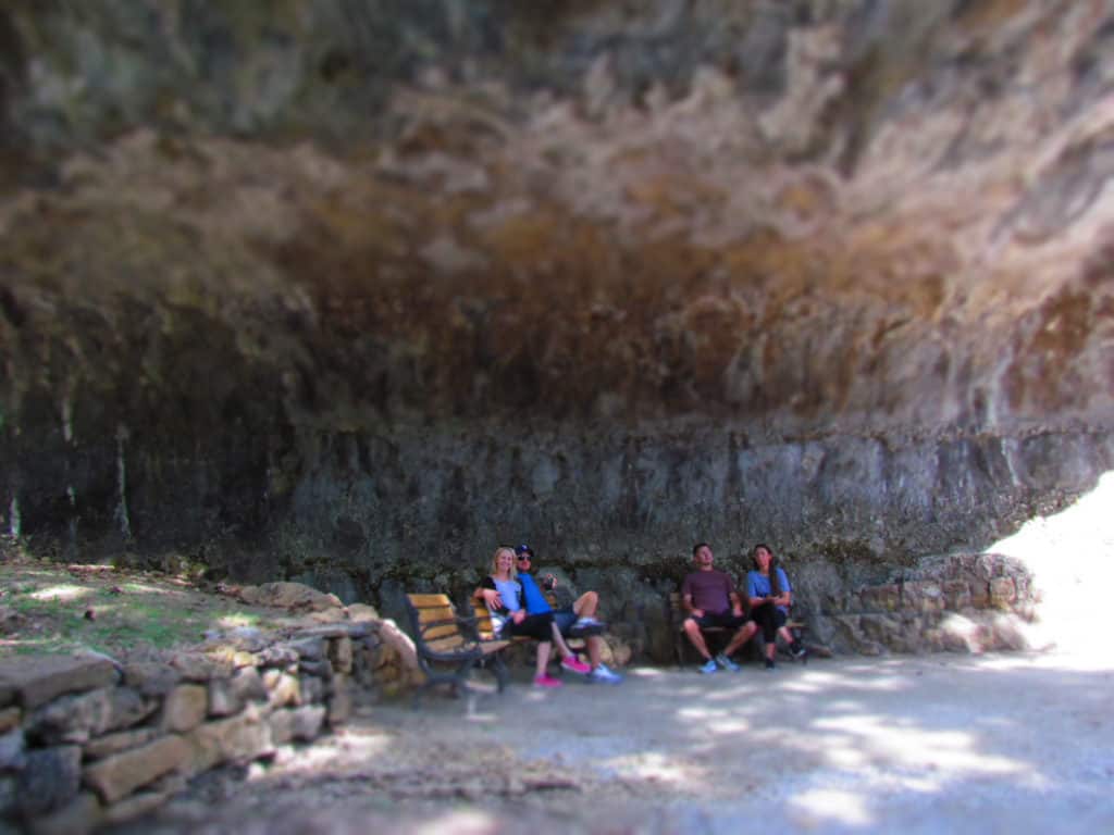 Visitors to Blue Spring Heritage Center take a short rest under the overhanging rock shelf.