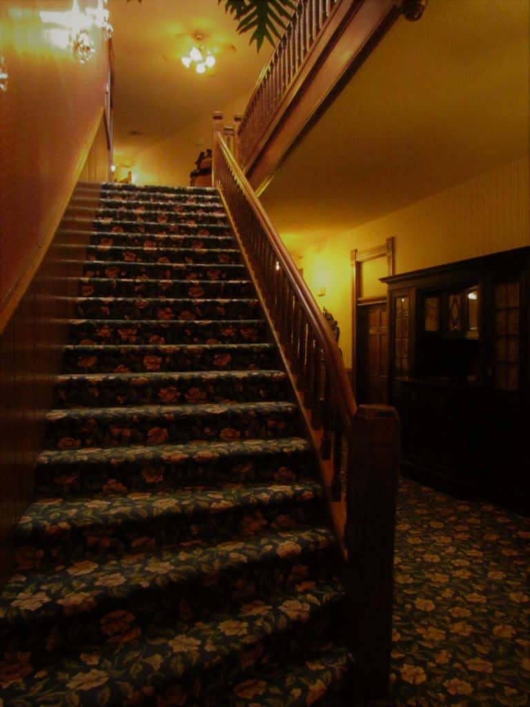 The century old staircase is bedecked with a Victorian floral carpet.