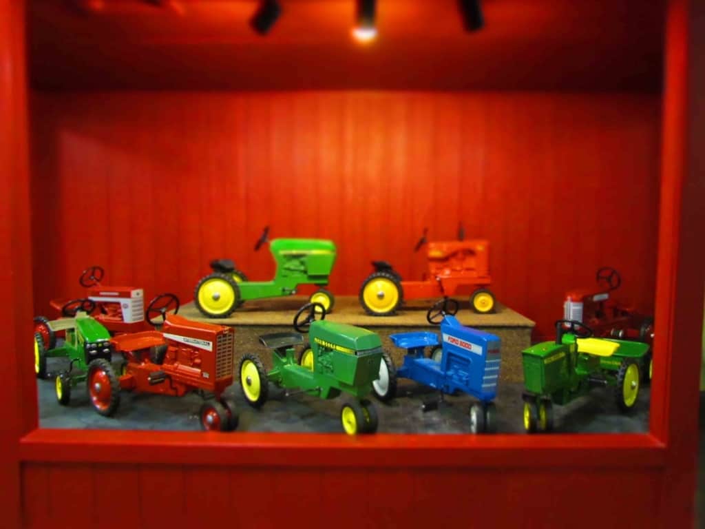 A display of pedal tractors are brightly colored and appealing to kids of all ages.
