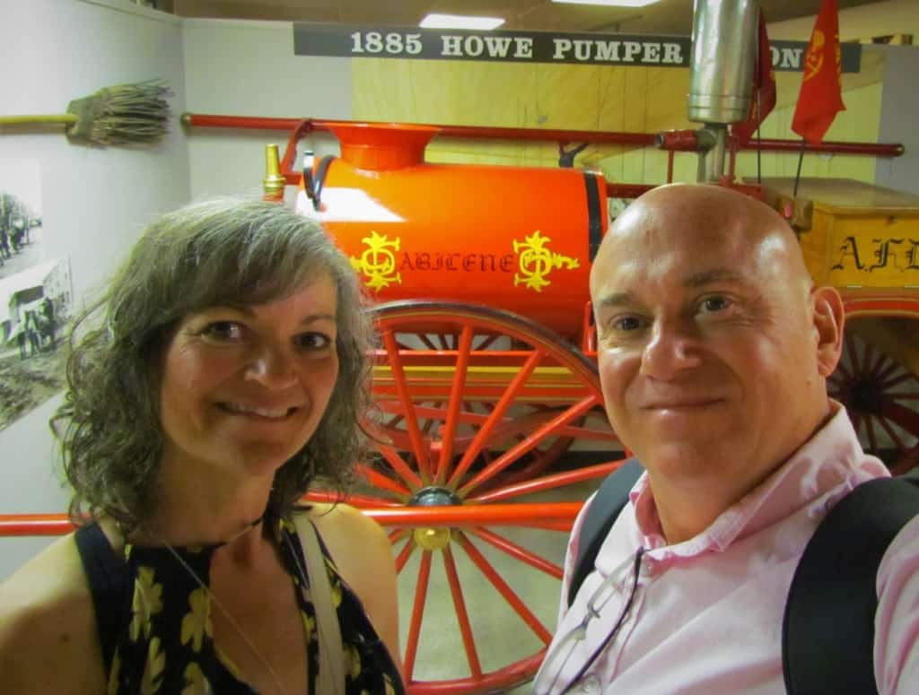 The authors pose for a selfie in front of an old piece of fire fighting equipment.