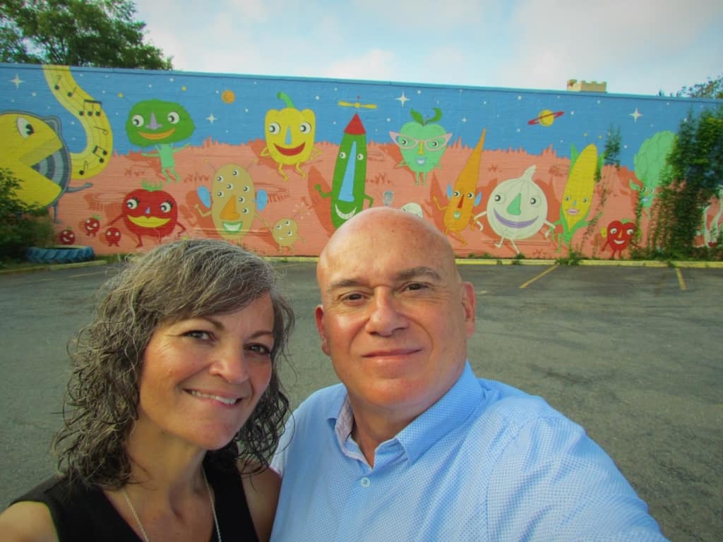 The authors pose for a selfie in front of the iconic mural located at The Root Cafe in Little Rock, Arkansas. 