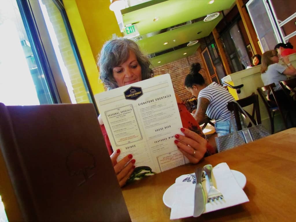Crystal scans the menu at Tupelo Honey Cafe to select the perfect lunch trio.