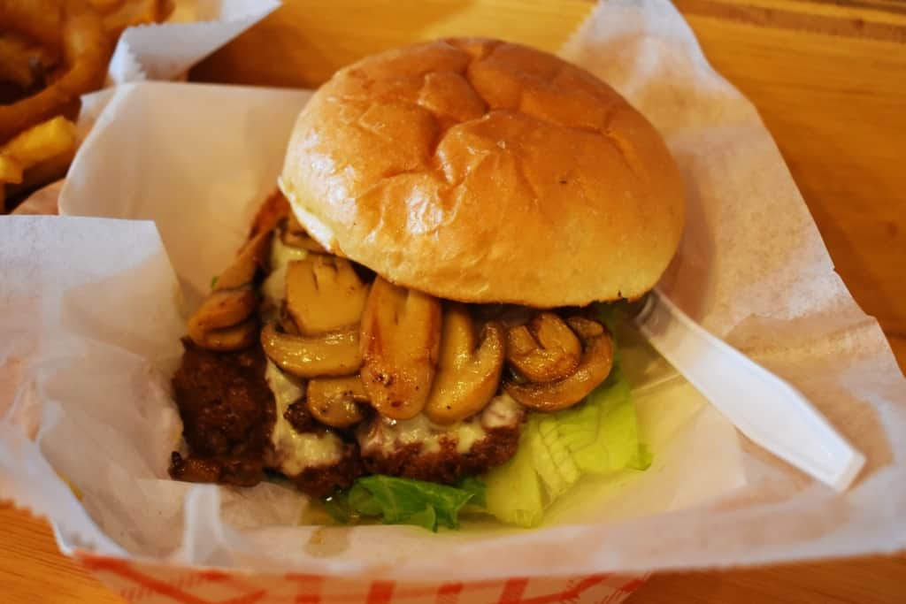 A quarter pound burger is topped with mushrooms and Swiss cheese to create a delectable dish. 