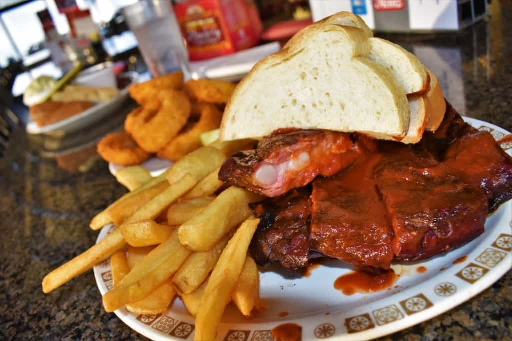 A plate of barbecue ribs pair well with french fries and onion rings. 