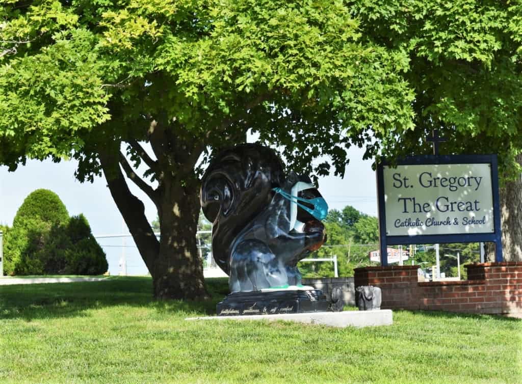 An iconic black squirrel statue rests near the entrance to a local Catholic school. 