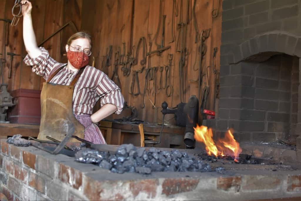 The blacksmith stokes the forge as she prepares to work a project. 