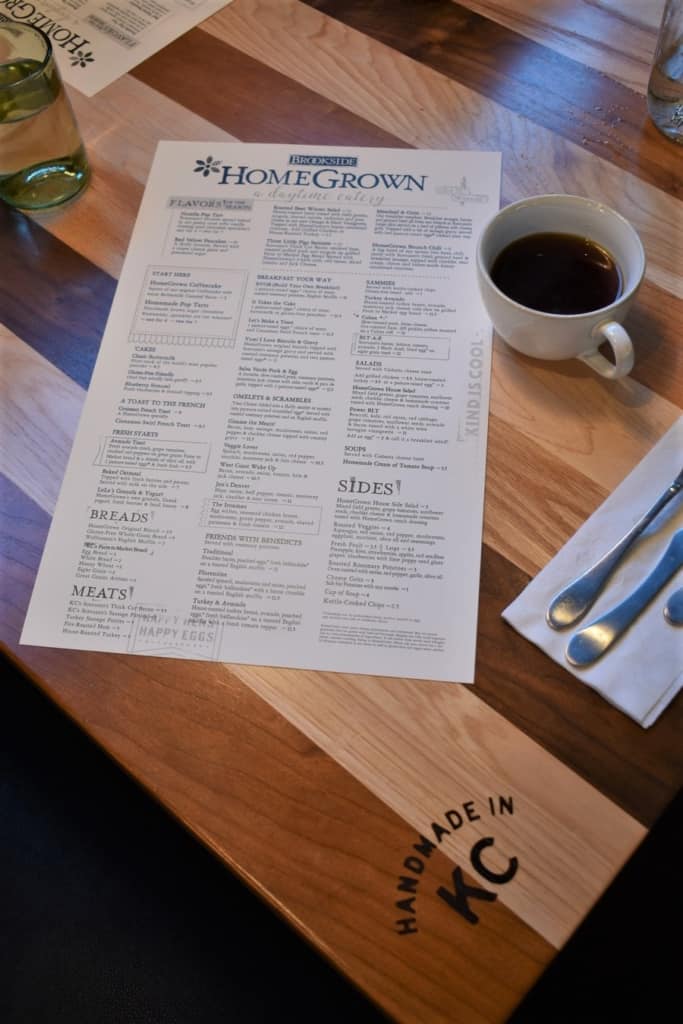 The menu from HomeGrown Kansas City sits on a table with a cup of coffee. 