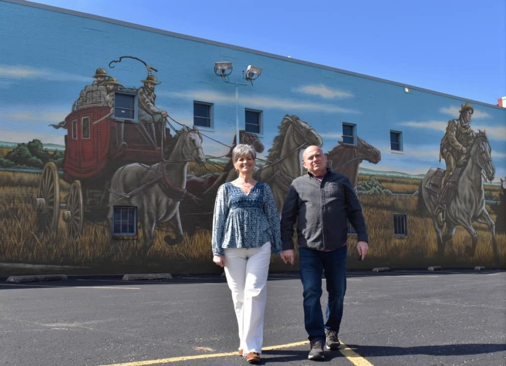 The authors pose for a selfie in front of a mural in St. Joseph, Missouri. 