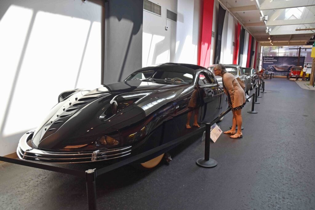The author peers into the window of a sleek car at the National Auto Museum.